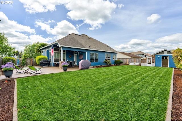 back of property featuring a patio, an outbuilding, and a shingled roof