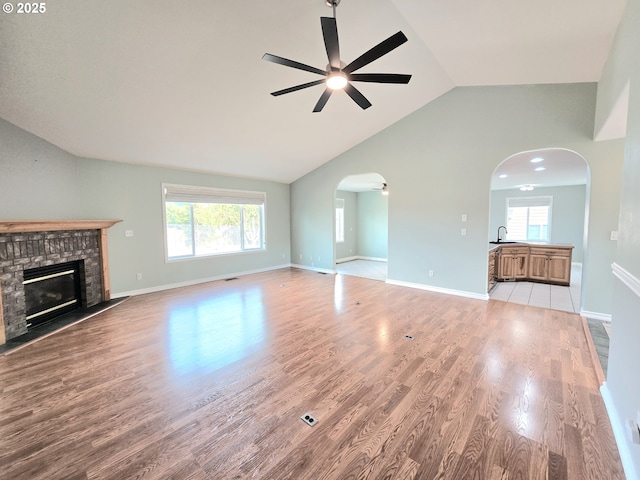 292 Jamie Loop, Roseburg, OR 97471 - unfurnished living room featuring a ceiling fan, arched walkways, vaulted ceiling, a brick fireplace, and wood finished floors