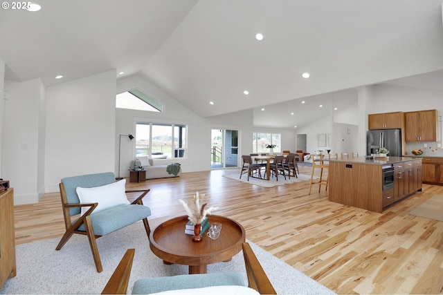 living area with light wood-style floors, high vaulted ceiling, and recessed lighting