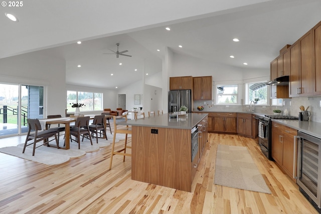 kitchen with beverage cooler, light wood-style flooring, a center island, black gas stove, and stainless steel refrigerator with ice dispenser