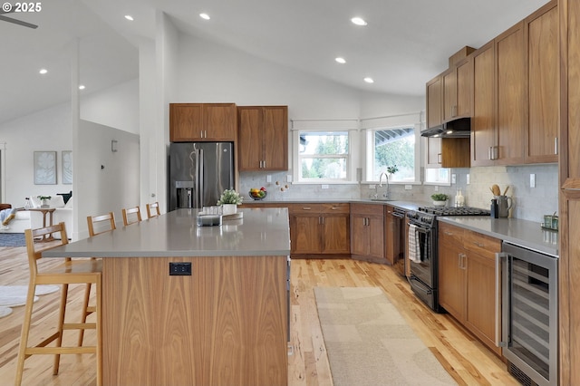 kitchen with beverage cooler, a kitchen bar, stainless steel fridge, light wood-style flooring, and gas stove