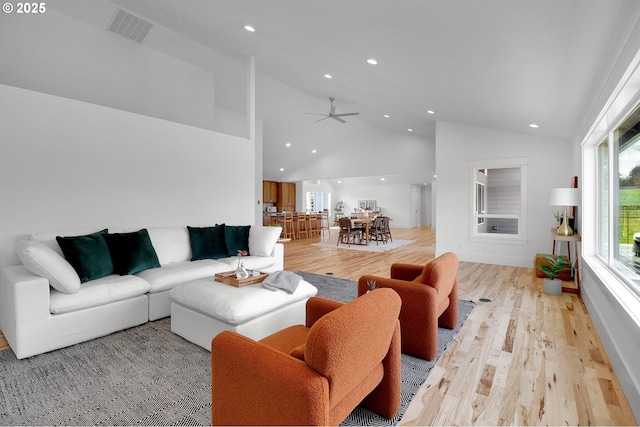 living room featuring high vaulted ceiling, light wood finished floors, recessed lighting, and visible vents