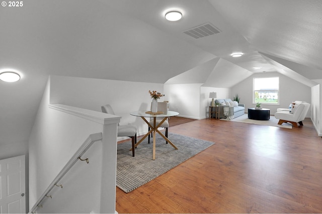 bedroom featuring baseboards, vaulted ceiling, wood finished floors, and visible vents