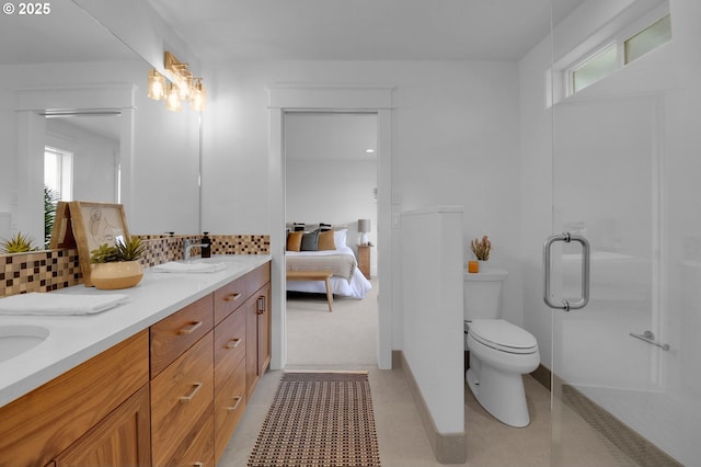 ensuite bathroom with backsplash, toilet, a healthy amount of sunlight, and double vanity