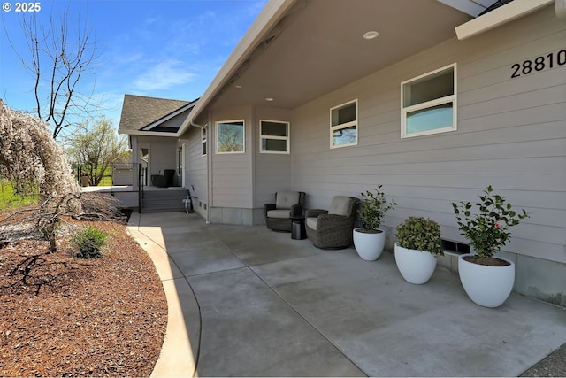 exterior space with roof with shingles and a patio area