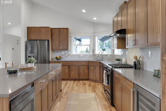 kitchen featuring stainless steel appliances, vaulted ceiling, beverage cooler, and light wood-style flooring