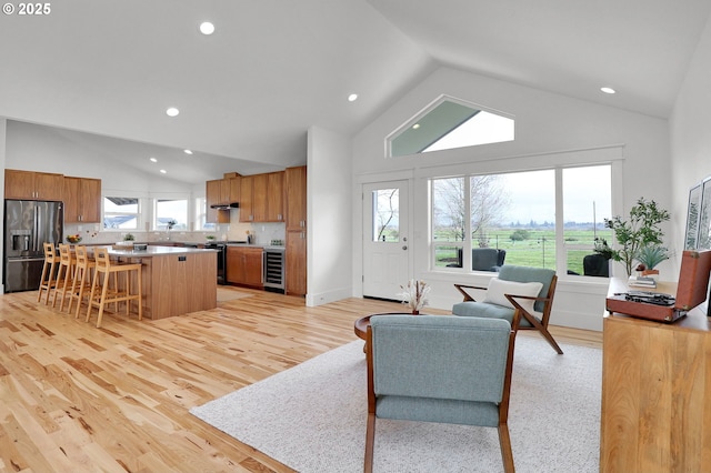 living room featuring light wood-style floors, high vaulted ceiling, recessed lighting, and beverage cooler