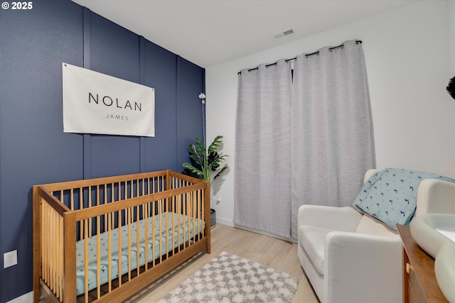 bedroom featuring wood finished floors and a crib