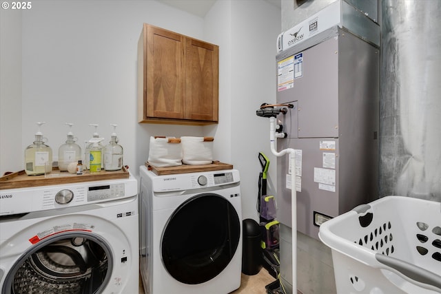 laundry room featuring washing machine and clothes dryer, cabinet space, and heating unit