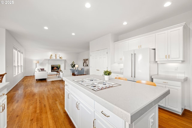 2360 Michael, West Linn, OR 97068 - kitchen featuring white appliances, white cabinets, light countertops, a warm lit fireplace, and a kitchen island