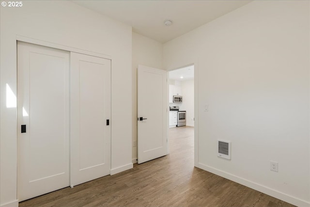unfurnished bedroom with wood finished floors, a closet, and baseboards