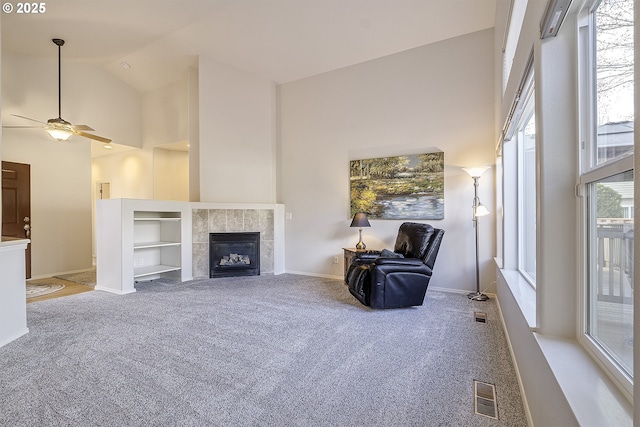 unfurnished living room with baseboards, visible vents, carpet floors, high vaulted ceiling, and a tiled fireplace