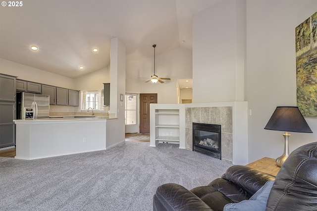 carpeted living room with ceiling fan, recessed lighting, a fireplace, and high vaulted ceiling