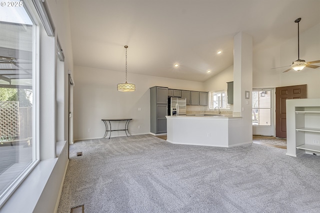 kitchen with a sink, stainless steel fridge, light carpet, and gray cabinets