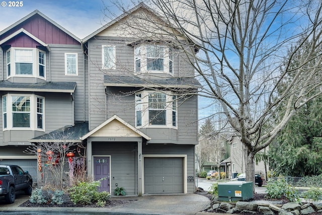 multi unit property with board and batten siding, a shingled roof, and a garage