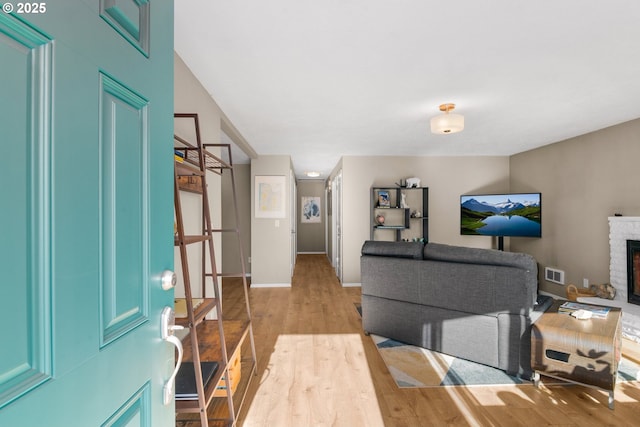 office space with visible vents, a fireplace, light wood-type flooring, and baseboards