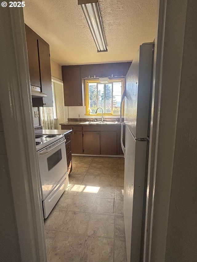 607 Commercial St, North Bend, OR 97459 - kitchen featuring a sink, white appliances, under cabinet range hood, a textured ceiling, and light floors