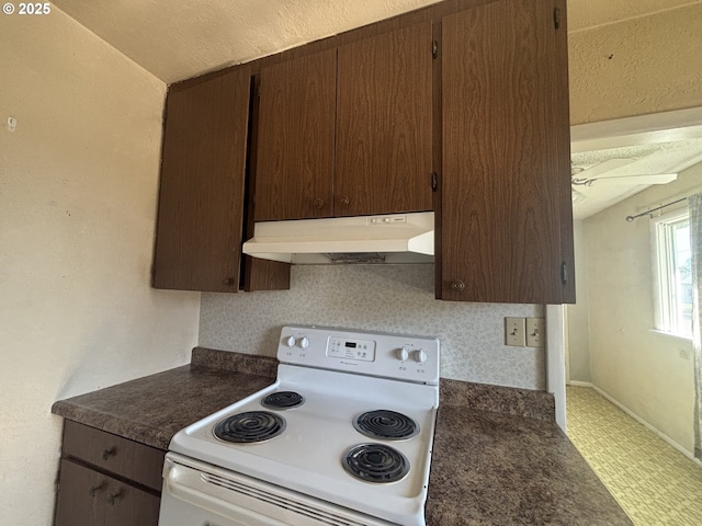 607 Commercial St, North Bend, OR 97459 - kitchen with electric range, under cabinet range hood, dark countertops, and dark brown cabinetry