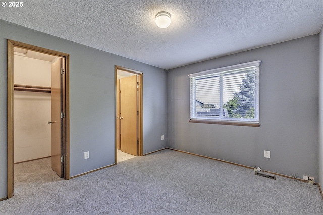 16541 NW Meadow Grass Ct, Beaverton, OR 97006 - unfurnished bedroom with a walk in closet, carpet flooring, a textured ceiling, and a closet
