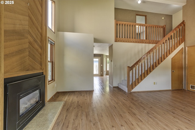 16541 NW Meadow Grass Ct, Beaverton, OR 97006 - unfurnished living room with a towering ceiling, stairway, wood finished floors, and a glass covered fireplace