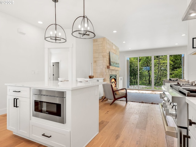 90190 Hobie Rd, Warrenton, OR 97146 - kitchen with a chandelier, open floor plan, light wood-style flooring, light countertops, and stainless steel microwave