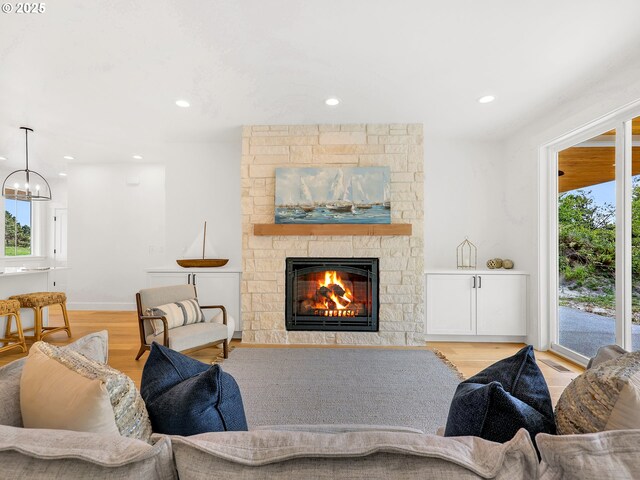 90190 Hobie Rd, Warrenton, OR 97146 - living area with wood finished floors, a stone fireplace, recessed lighting, and a chandelier
