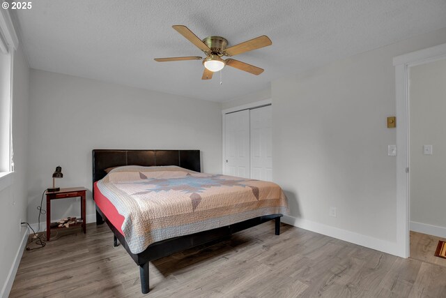 bedroom featuring baseboards, a ceiling fan, wood finished floors, a textured ceiling, and a closet