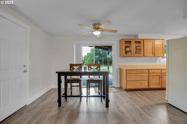 dining space featuring light wood-style flooring, baseboards, and a ceiling fan