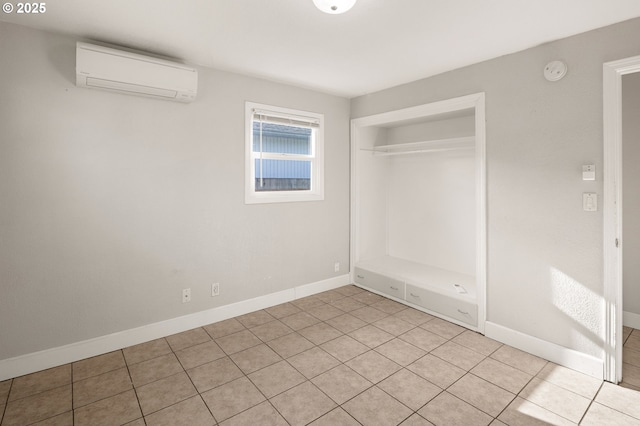 unfurnished bedroom with a closet, a wall mounted air conditioner, and light tile patterned floors