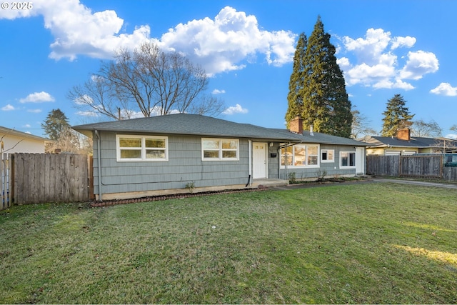 view of front of house with a fenced backyard, a chimney, and a front yard