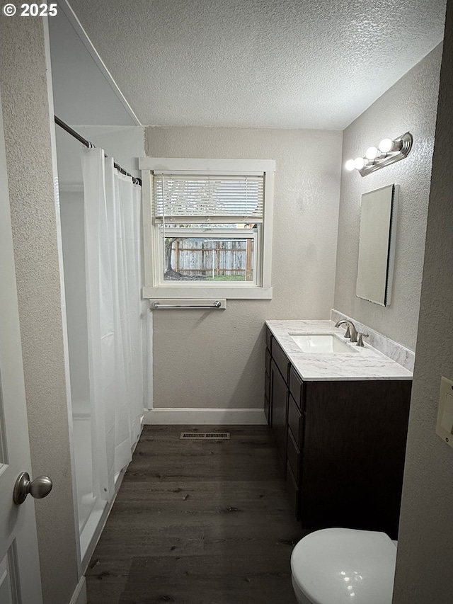 bathroom with toilet, wood-type flooring, a textured ceiling, a shower with shower curtain, and vanity