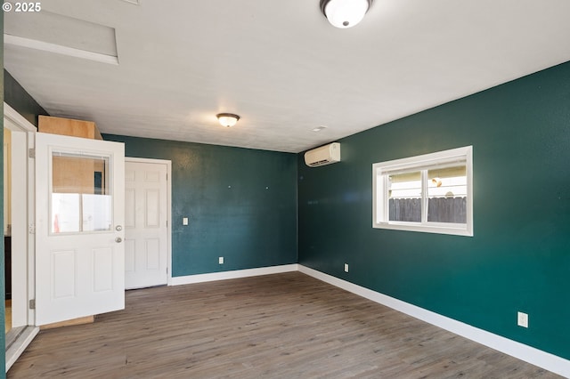 spare room featuring a wall mounted air conditioner and hardwood / wood-style floors