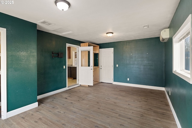 spare room with a wall mounted AC and wood-type flooring