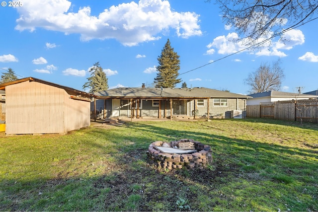 back of property with an outdoor fire pit and a lawn