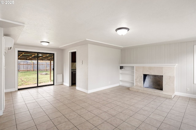 unfurnished living room featuring a wall unit AC, a high end fireplace, and a textured ceiling