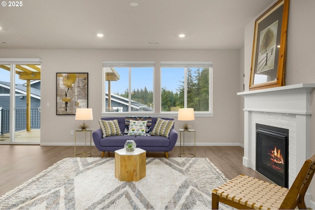 living area featuring visible vents, baseboards, recessed lighting, wood finished floors, and a glass covered fireplace