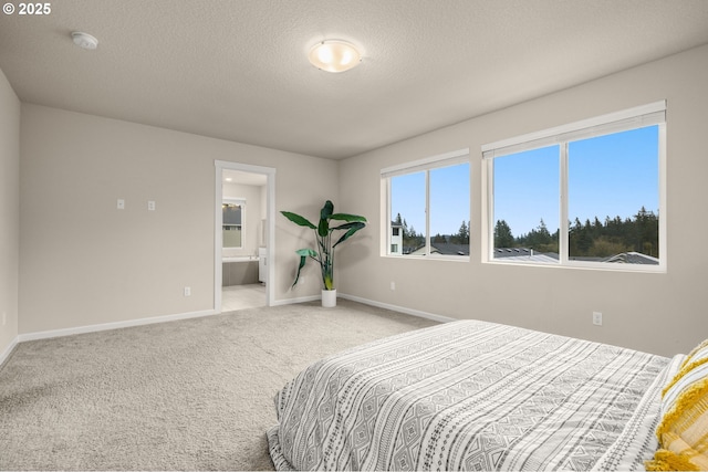 bedroom featuring baseboards, carpet, ensuite bathroom, and a textured ceiling