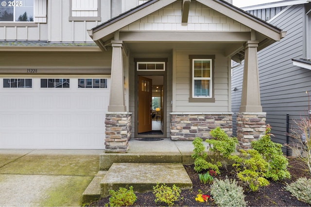 doorway to property featuring stone siding, an attached garage, driveway, and board and batten siding