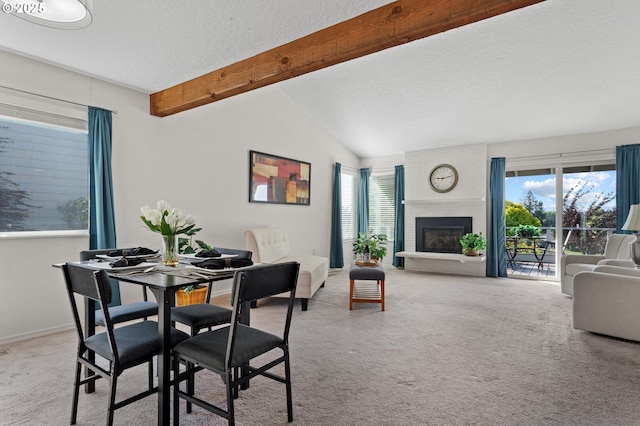 carpeted dining space with a brick fireplace, vaulted ceiling with beams, a textured ceiling, and a healthy amount of sunlight