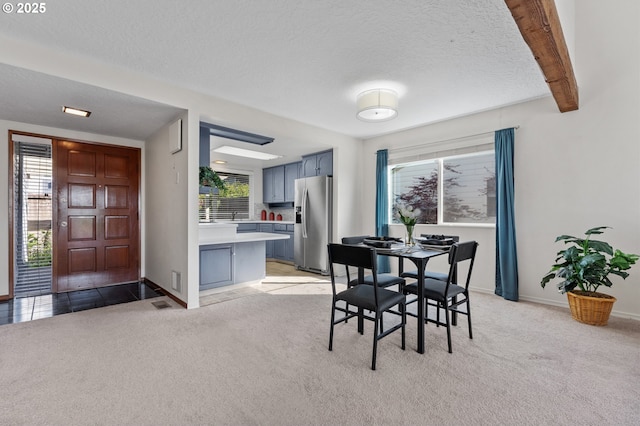 dining area with a textured ceiling, light carpet, baseboards, and plenty of natural light