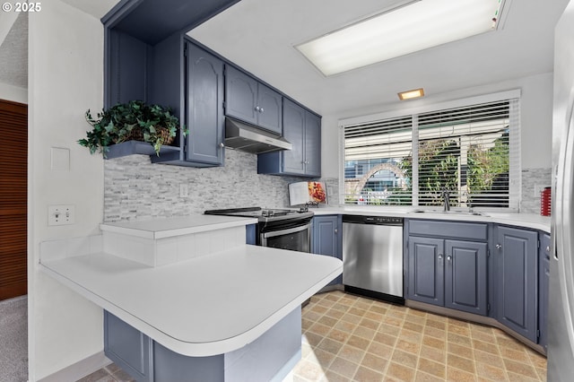 kitchen featuring a peninsula, light countertops, under cabinet range hood, tasteful backsplash, and stainless steel appliances