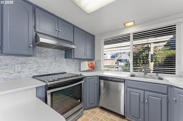 kitchen featuring exhaust hood, a sink, light countertops, stainless steel appliances, and decorative backsplash