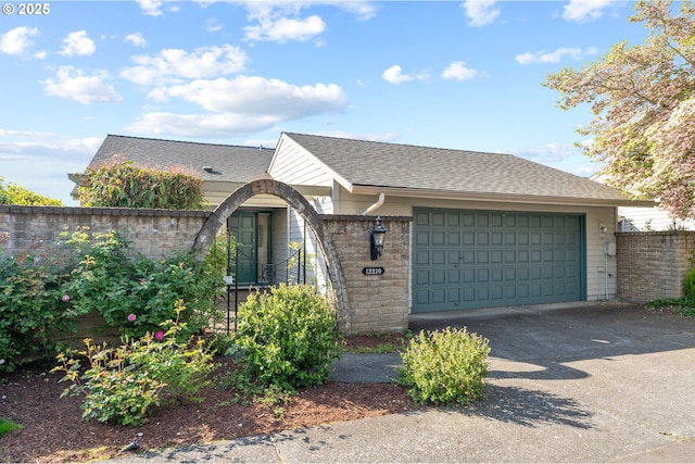 view of front of house featuring a garage, fence, stone siding, roof with shingles, and driveway