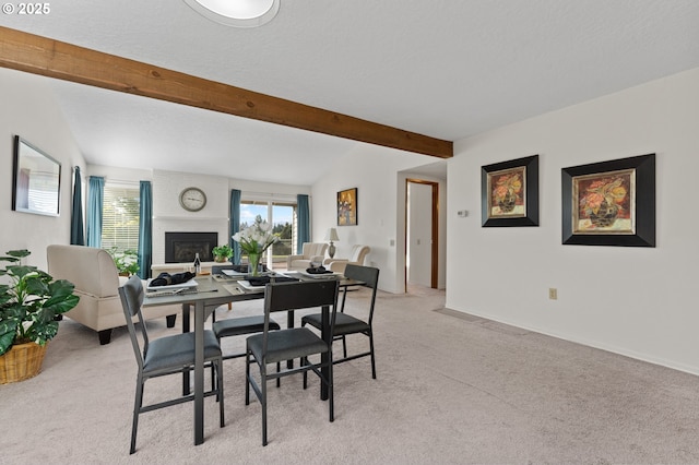 dining area featuring a fireplace, beam ceiling, and light colored carpet