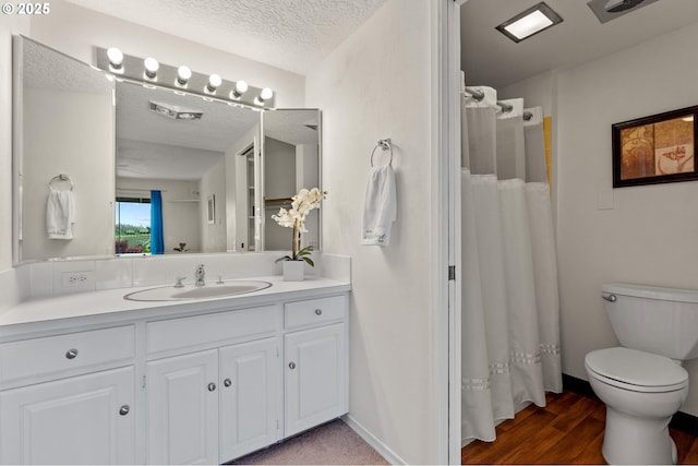 full bathroom with vanity, wood finished floors, curtained shower, toilet, and a textured ceiling