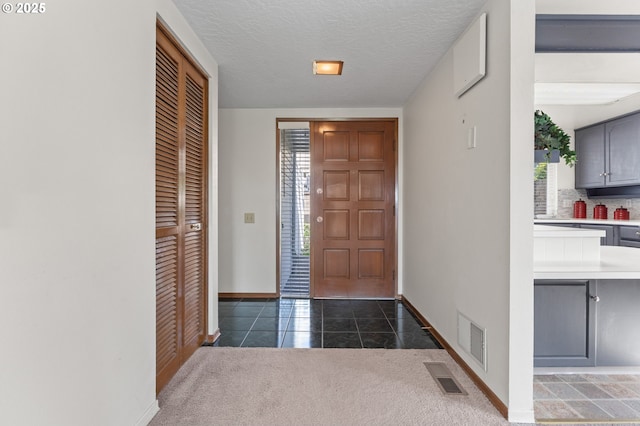 entryway featuring dark tile patterned floors, baseboards, visible vents, and a textured ceiling
