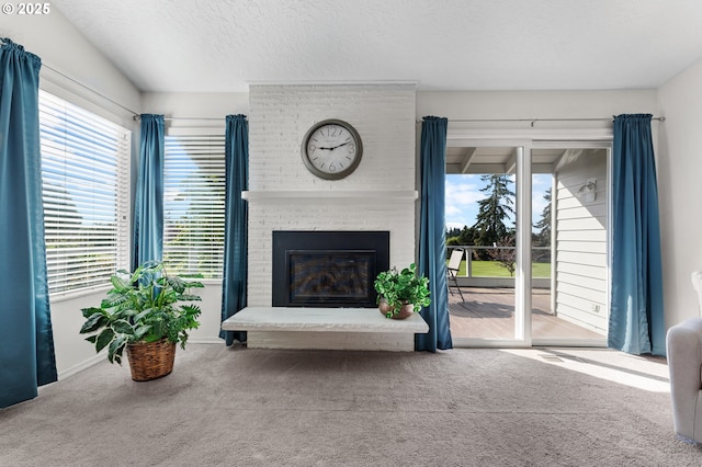 living area with carpet floors, a textured ceiling, baseboards, and a brick fireplace