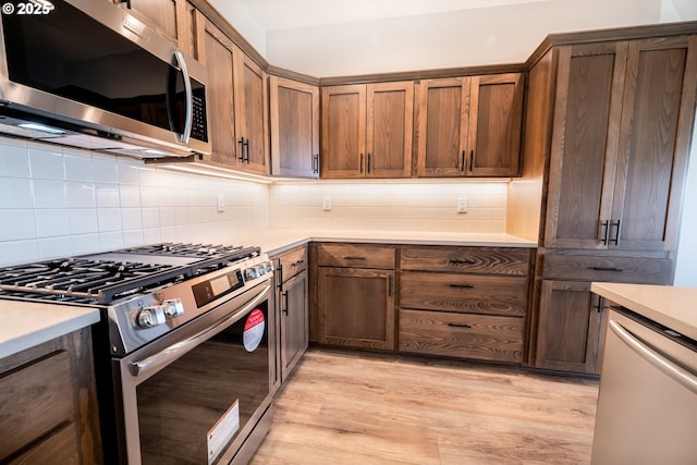 kitchen featuring backsplash, light hardwood / wood-style floors, and appliances with stainless steel finishes