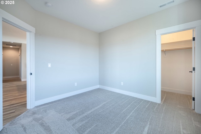 unfurnished bedroom with a walk in closet, carpet flooring, and a closet