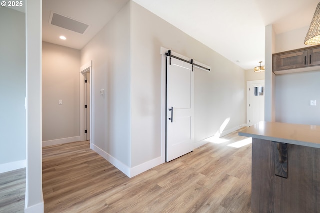 hallway with a barn door and light wood-type flooring